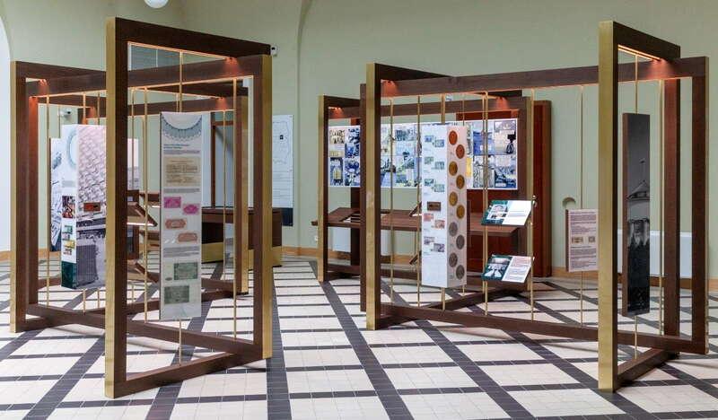Sala muzealna z eksponatami rozwieszonymi na sztalugach.