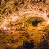 Oświetlona sala w Jaskini Wierzchowskiej Górnej. Na dnie jaskini stalagmity.