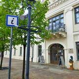Budynek w którym znajduje się punkt informacji turystycznej w Olkuszu, przed budynkiem drogowskaz do punktu informacji - litera 