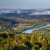 Widok z góry na Gminę Pleśna, czyli zalesione okolice Dunajca. Gdzieniegdzie widoczne są domy, a nad lasami unosi się mgła.