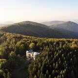 Obserwatorium astronomiczne na górze Lubomir. Wokół roztaczają się zielone połacie drzew.