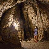 Widok na wnętrze Jaskini Wierzchowskiej Górnej. Pośrodku kobieta spoglądająca na wnętrze jaskini.