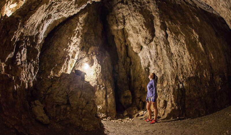 Widok na wnętrze Jaskini Wierzchowskiej Górnej. Pośrodku kobieta spoglądająca na wnętrze jaskini.