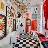 Kolorowe pomieszczenie, podłoga w czarno-białą szachownicę, czarne i czerwone elementy do gry w karty na ścianach jako dekoracje