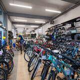 Dziesiątki rowerów ustawionych w rzędzie, na półkach akcesoria rowerowe.