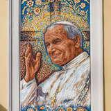 Nad ozdobnym gzymsem w budynku okno z kolorową mozaiką z wizerunkiem do połowy papieża Jana Pawła II, w białej albie z wiszącym krzyżem, z białą piuską na głowie, z siwymi włosami i uśmiechem na twarzy. Prawa ręka uniesiona do błogosławieństwa. Za postacią rozświetlony krzyż i na około kwiaty.